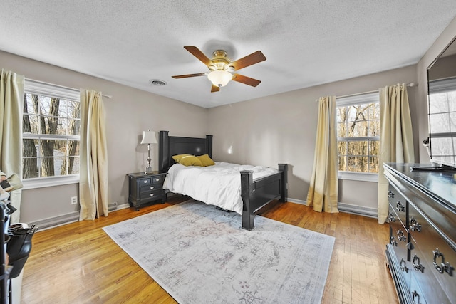 bedroom with multiple windows, light wood-style floors, visible vents, and baseboards