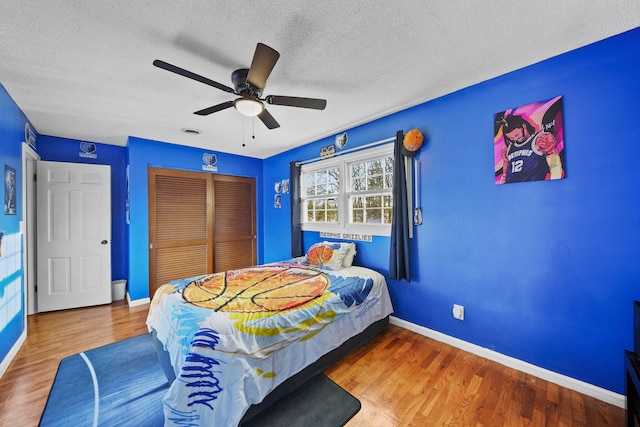 bedroom featuring a closet, baseboards, a textured ceiling, and wood finished floors