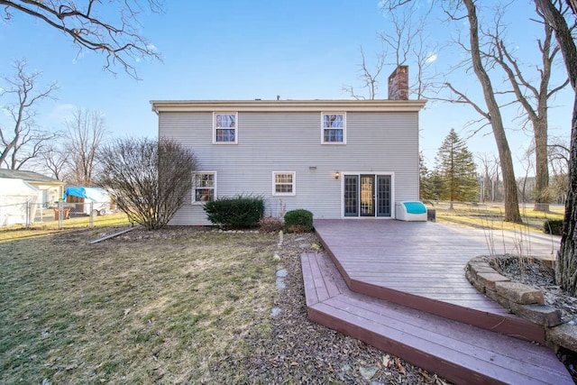 rear view of house with a wooden deck, a yard, a chimney, and fence