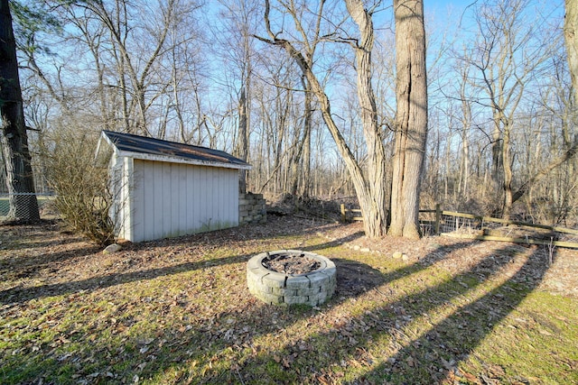 view of yard featuring a storage shed, a fire pit, fence, and an outbuilding