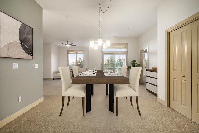 dining room with ceiling fan with notable chandelier, baseboards, and light carpet