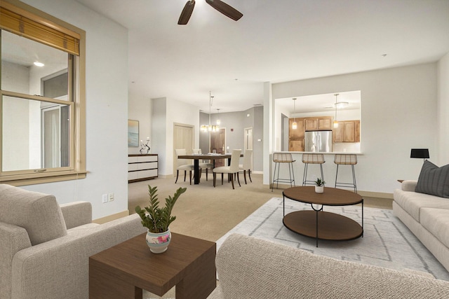 living area with light colored carpet, baseboards, and ceiling fan