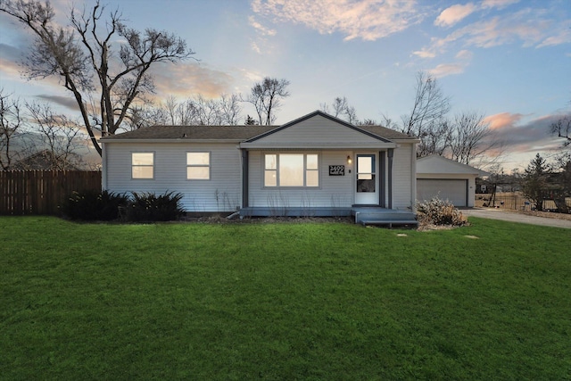 view of front facade with an outbuilding, driveway, fence, a front yard, and a garage