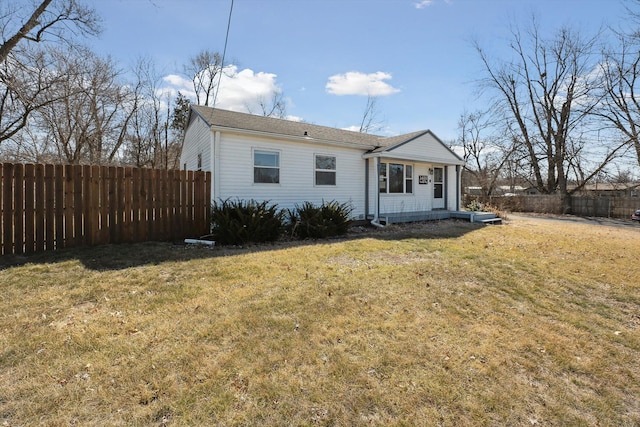 back of property with a lawn and fence