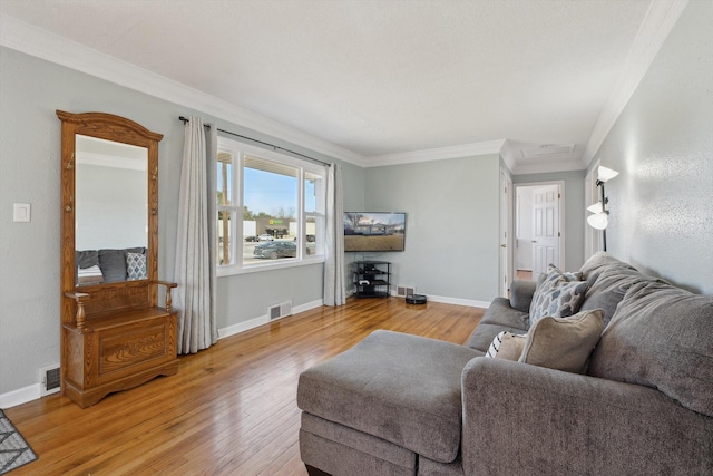 living room with light wood finished floors, visible vents, baseboards, and ornamental molding