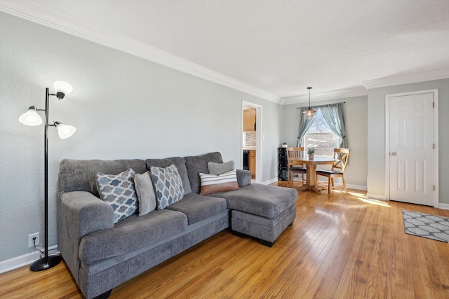 living room with crown molding, light wood-style floors, and baseboards