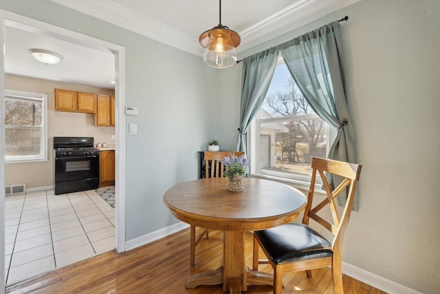 dining room with visible vents, baseboards, crown molding, and light wood-style floors