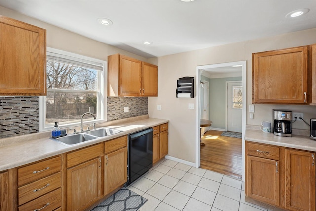 kitchen with a sink, black dishwasher, light countertops, and light tile patterned floors