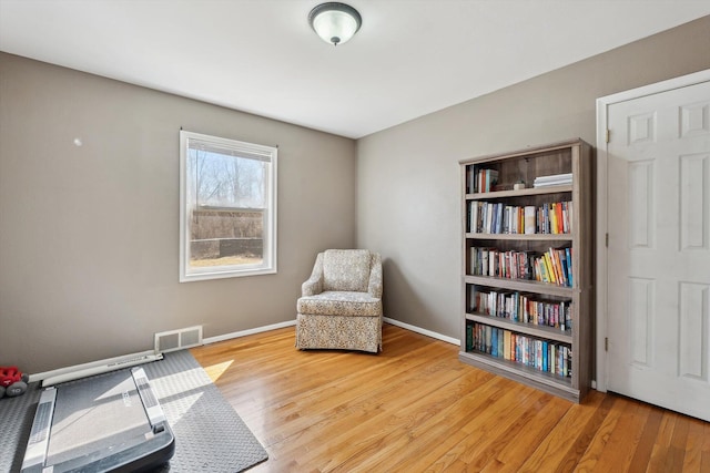 living area featuring visible vents, baseboards, and wood finished floors