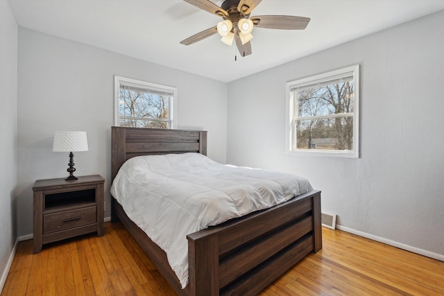 bedroom featuring multiple windows, baseboards, and light wood finished floors