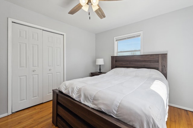 bedroom featuring ceiling fan, a closet, baseboards, and wood finished floors