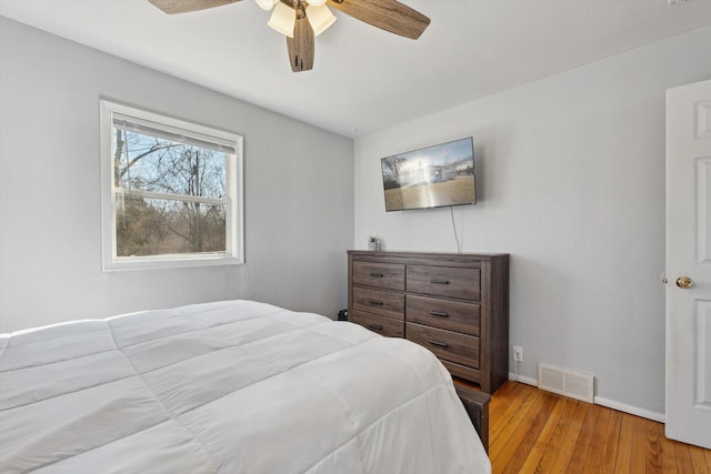 bedroom with visible vents, ceiling fan, baseboards, and hardwood / wood-style floors