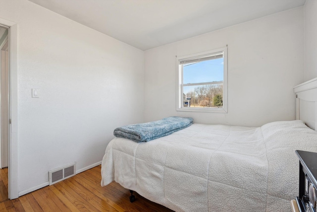 bedroom featuring visible vents, baseboards, and wood finished floors