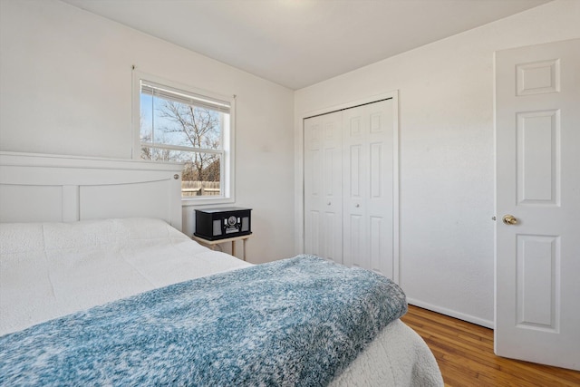 bedroom with wood finished floors, a closet, and baseboards