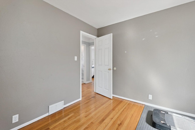 unfurnished room with wood finished floors, visible vents, and baseboards