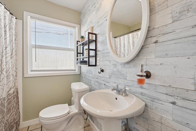 bathroom featuring a sink, baseboards, toilet, and wood walls