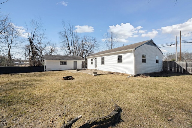 back of property featuring an outdoor structure, a yard, fence, and an outdoor fire pit