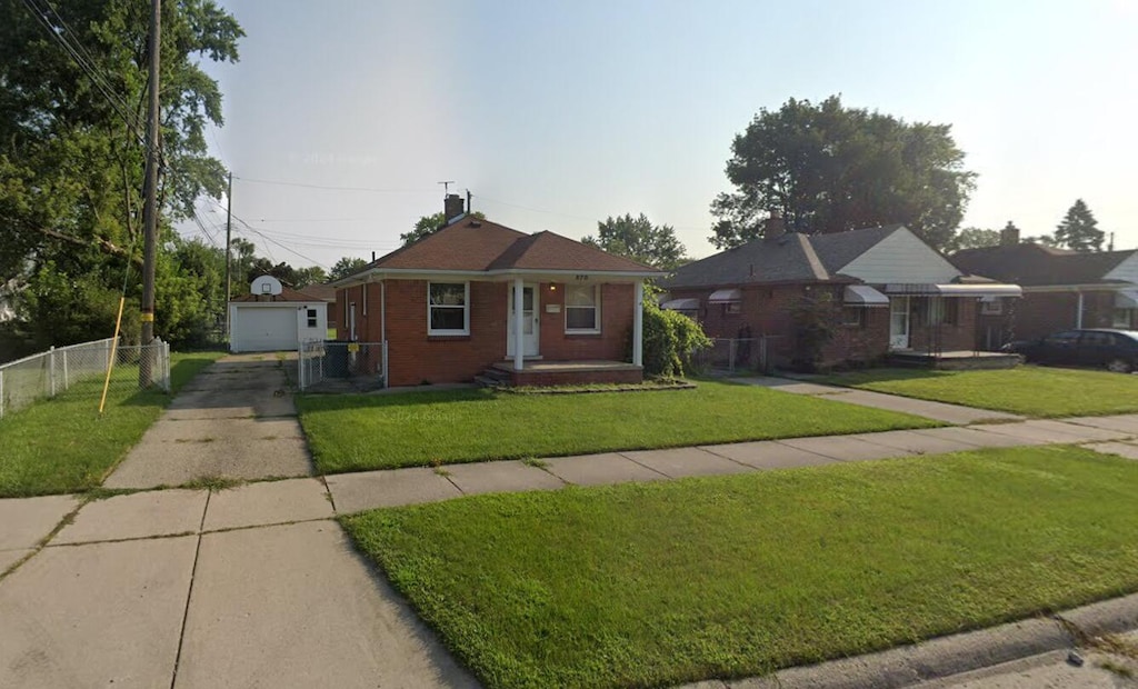 view of front of home with an outdoor structure, concrete driveway, a front lawn, and fence