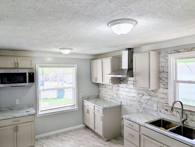 870 Capitol Ave, Lincoln Park, MI 48146 - kitchen featuring wall chimney range hood, a sink, stainless steel microwave, light marble finish flooring, and decorative backsplash