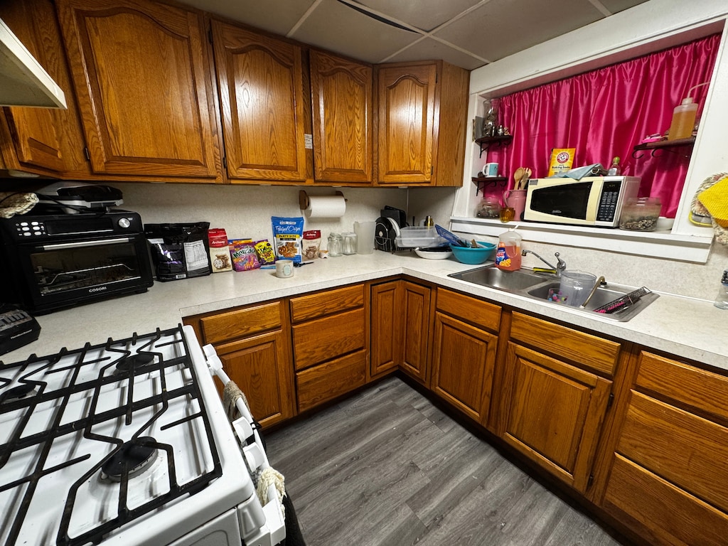 kitchen with white appliances, light countertops, brown cabinets, and a sink