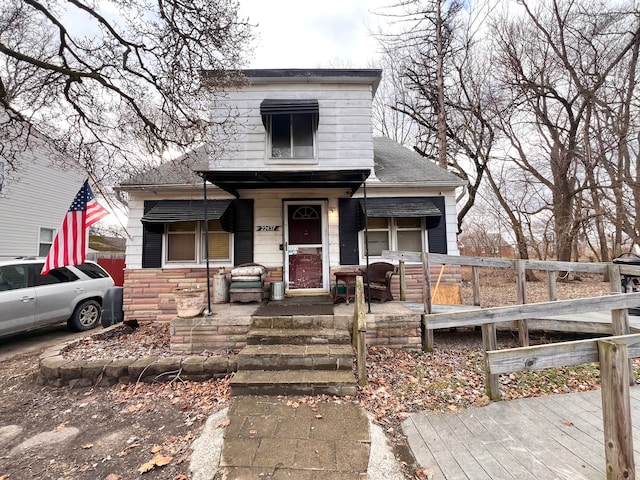 bungalow featuring stone siding, roof with shingles, and covered porch