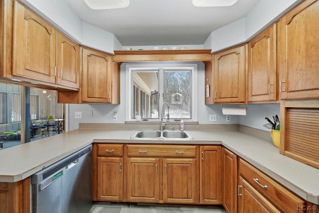 kitchen with a peninsula, a sink, light countertops, stainless steel dishwasher, and brown cabinets