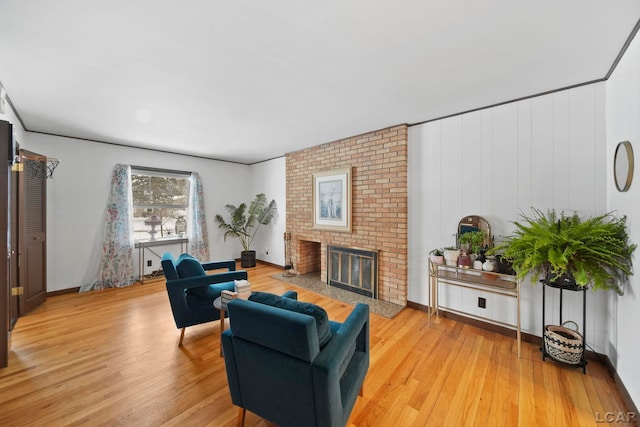 living area featuring light wood-type flooring and a brick fireplace