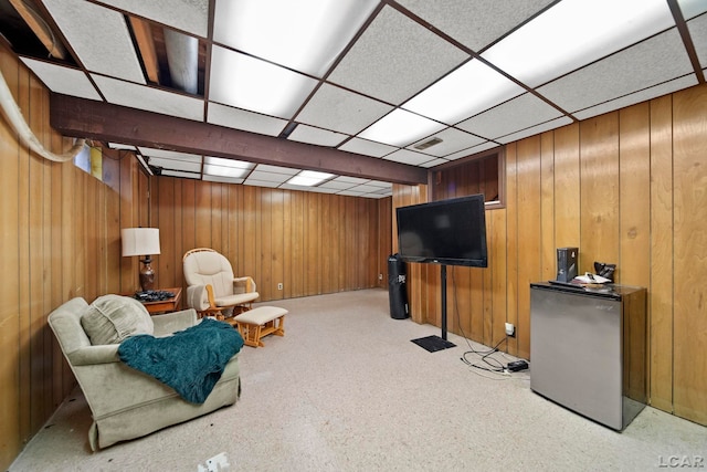 sitting room with wooden walls, visible vents, and a drop ceiling