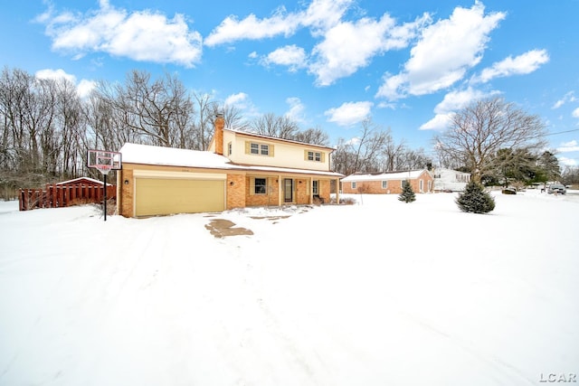 snow covered house featuring brick siding, a chimney, and an attached garage