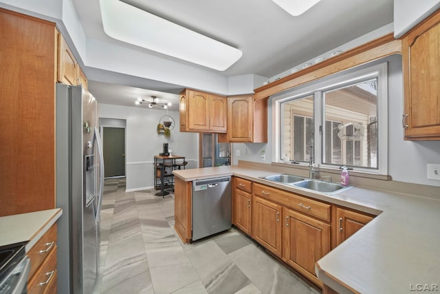 kitchen featuring a sink, stainless steel appliances, a peninsula, and light countertops