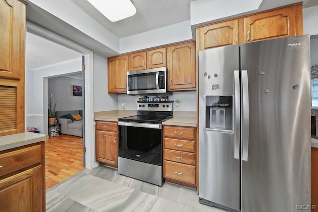 kitchen featuring brown cabinets, appliances with stainless steel finishes, ornamental molding, and light countertops