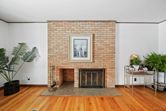 living room featuring a fireplace, crown molding, wood finished floors, and baseboards