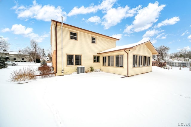 snow covered back of property featuring central AC unit