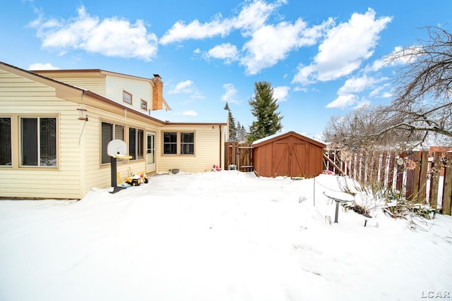 yard layered in snow with an outbuilding, a shed, and fence