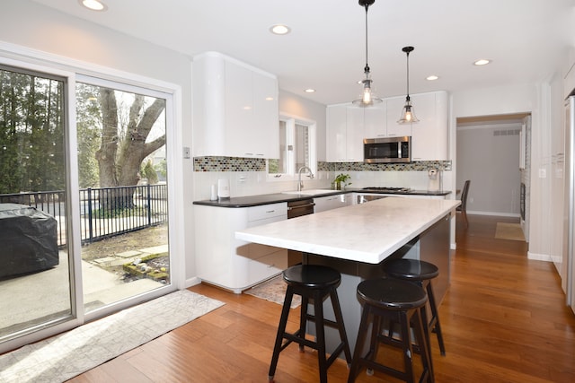 kitchen featuring decorative backsplash, stainless steel microwave, white cabinets, and a kitchen island