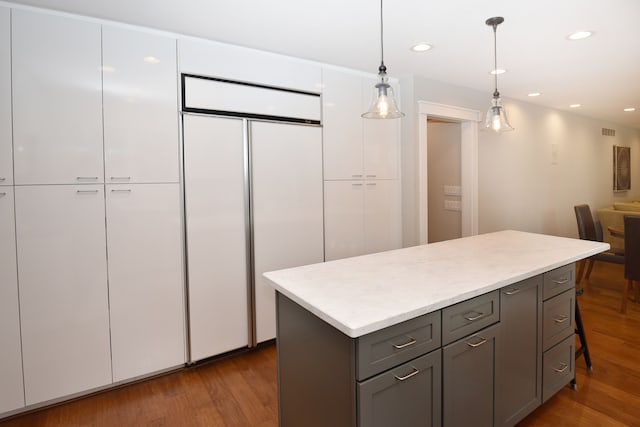 kitchen with a center island, gray cabinets, wood finished floors, white cabinetry, and built in fridge