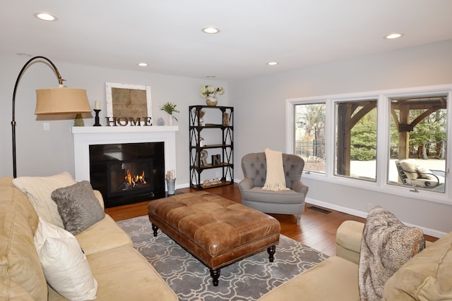 living room with recessed lighting, visible vents, a glass covered fireplace, and wood finished floors