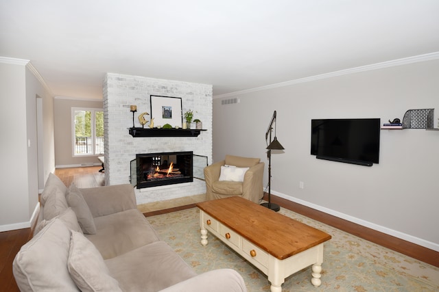 living area featuring baseboards, wood finished floors, a fireplace, and ornamental molding