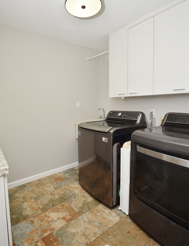 laundry area with stone finish floor, cabinet space, baseboards, and washer and clothes dryer