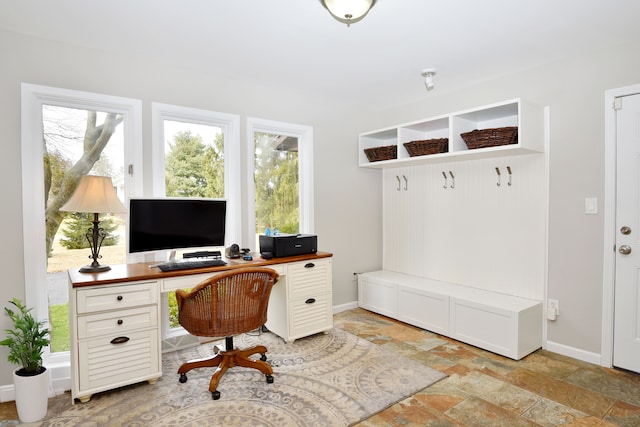 home office featuring stone tile floors and baseboards