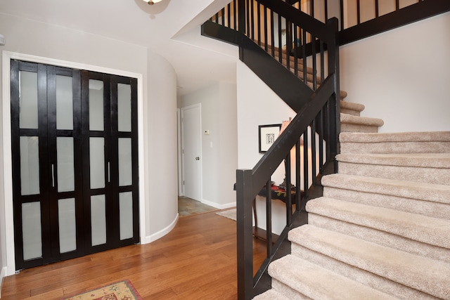 entryway featuring baseboards, wood finished floors, and stairs