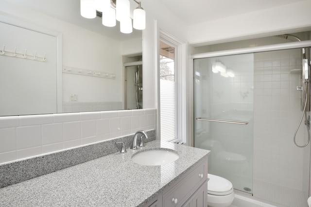 bathroom with vanity, toilet, tasteful backsplash, and a stall shower