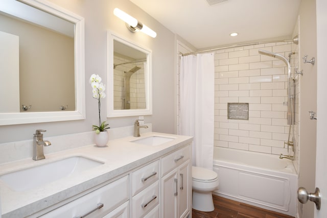 bathroom featuring a sink, toilet, wood finished floors, and double vanity