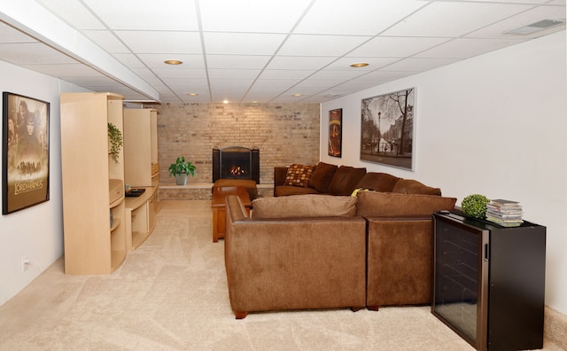 living room with a drop ceiling, visible vents, light colored carpet, and a fireplace