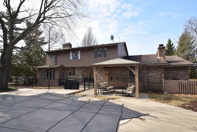 rear view of property with brick siding, fence, an outdoor hangout area, a chimney, and a patio area