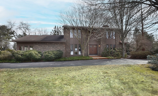 view of front facade with a front yard, brick siding, and a chimney