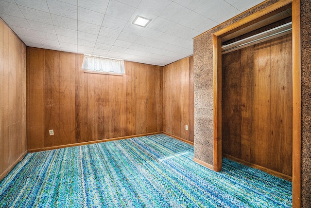 basement featuring wood walls and carpet