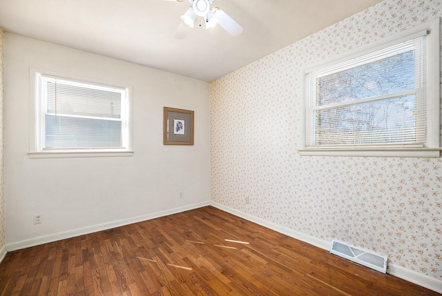 empty room with wallpapered walls, dark wood-type flooring, baseboards, and visible vents