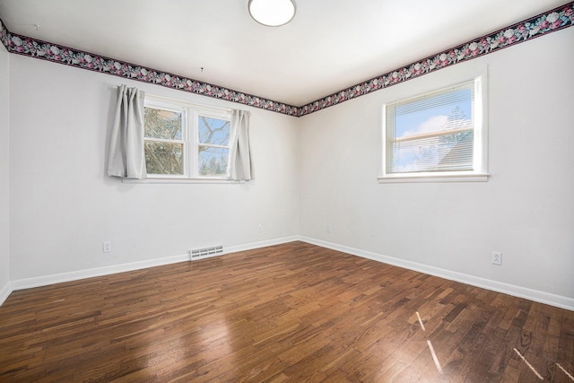 spare room featuring baseboards and wood-type flooring