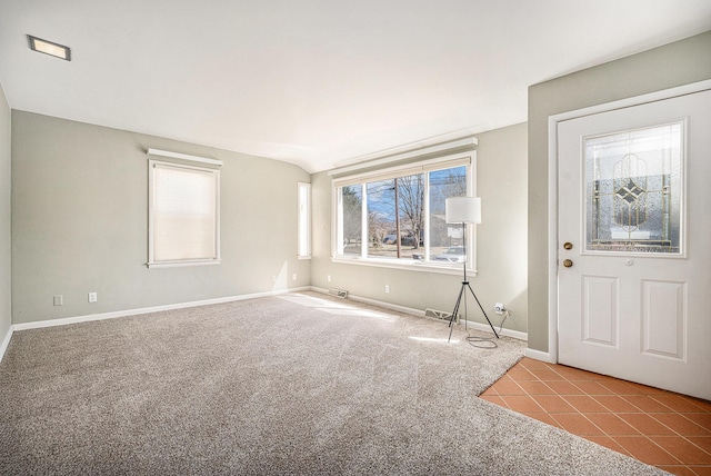 carpeted foyer featuring baseboards, tile patterned flooring, and vaulted ceiling